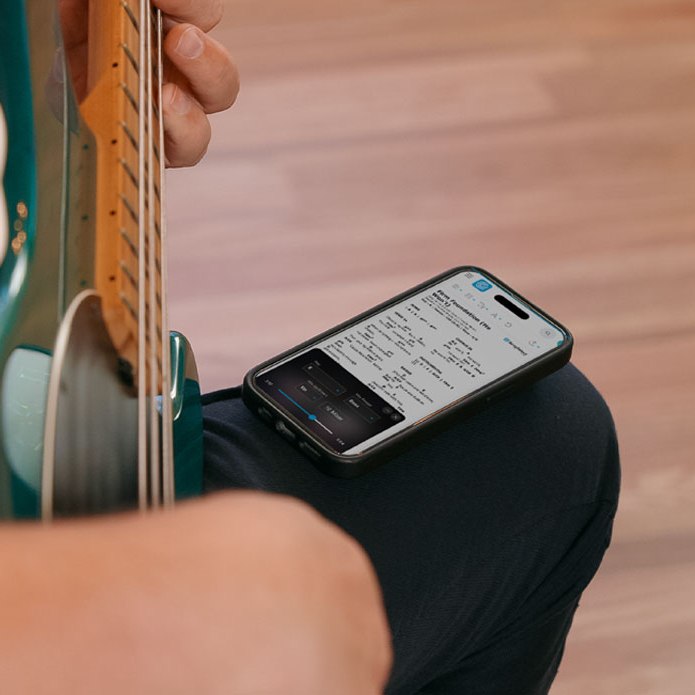 A bass player practicing along to the Rehearse app on their phone