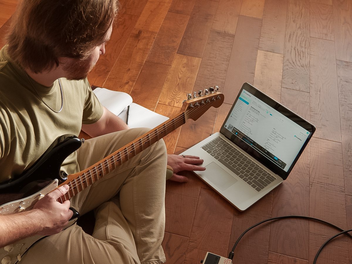 A guitarist practicing along to Rehearse on a laptop