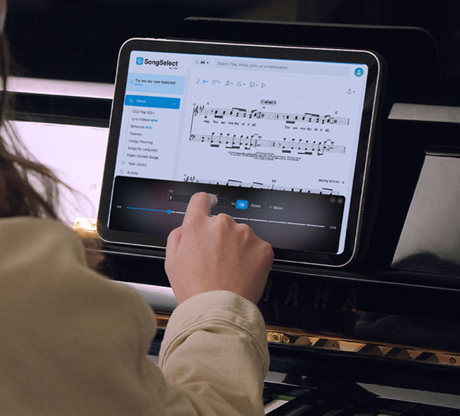 A musician at a piano following sheet music in SongSelect while using Rehearse to set the key, tempo, and mix